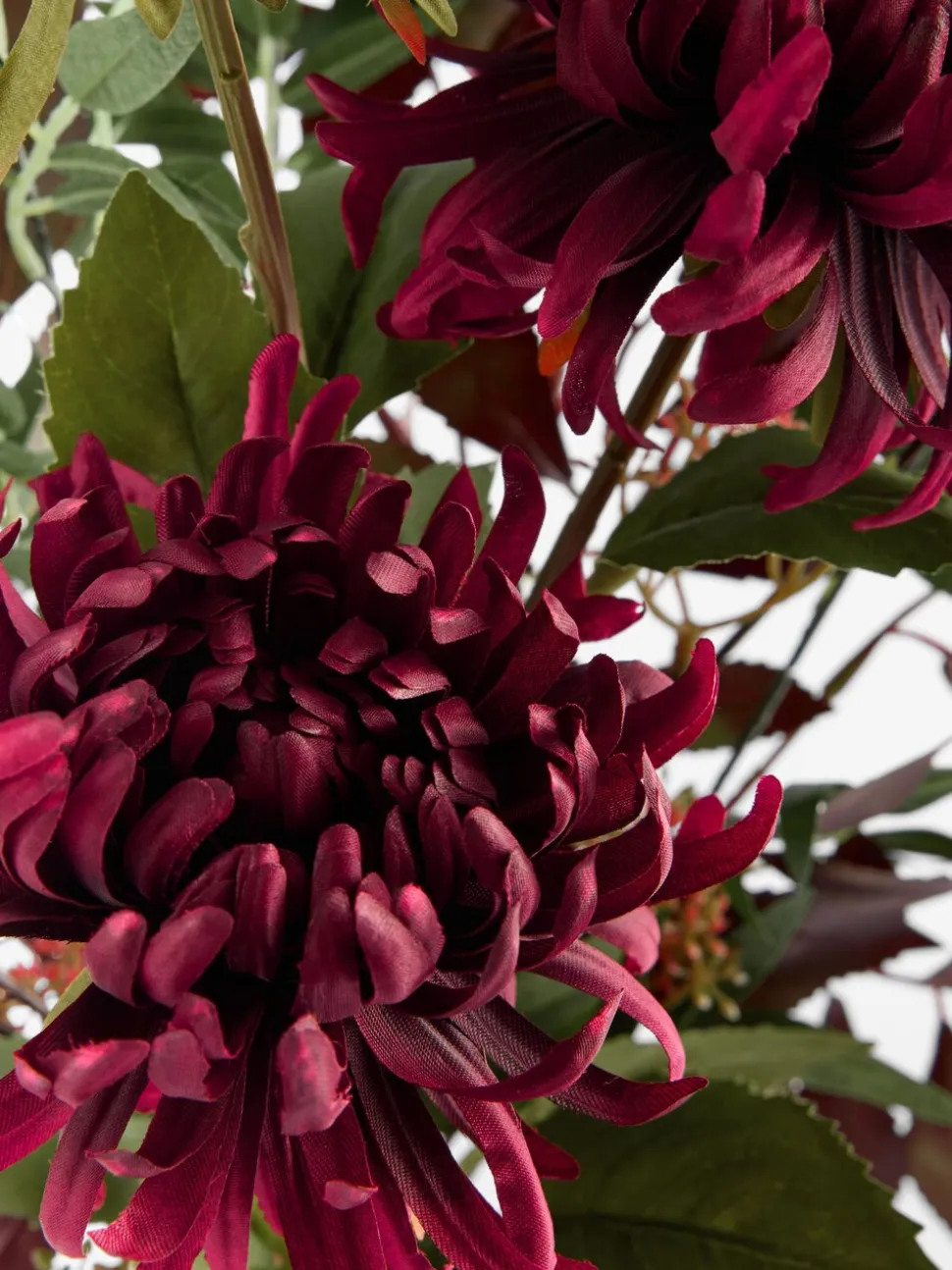 Kunstbloemstuk met donkere bloemen in keramische vaas